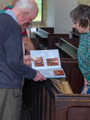 Visitors viewing a photo album brought in by a past resident.